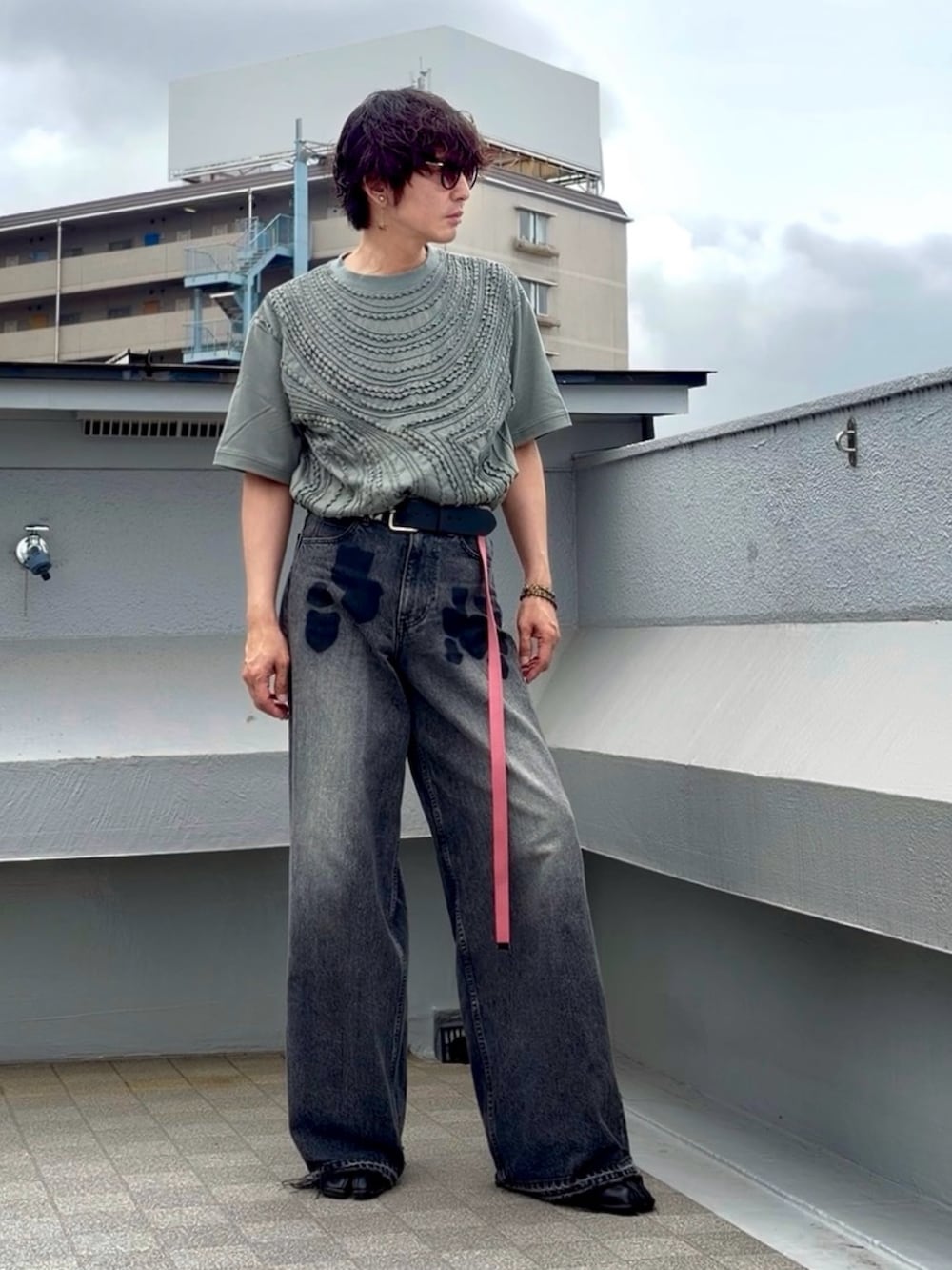 ブラック系のデニムパンツ、ブラック系のブーツ、グリーン系のTシャツ/カットソーを着用したメンズの夏コーディネートの4枚目の写真