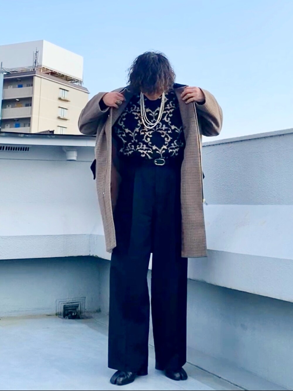 ブラウン系のステンカラーコート、ブラック系のニット/セーター、ブラック系のスラックスを着用したメンズの冬コーディネートの5枚目の写真