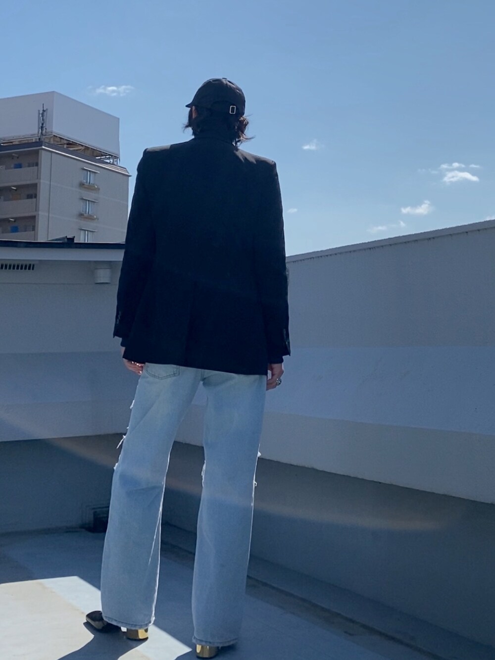 ブラック系のテーラードジャケット、ブルー系のジャージ、ブルー系のデニムパンツを着用したメンズの春コーディネートの4枚目の写真