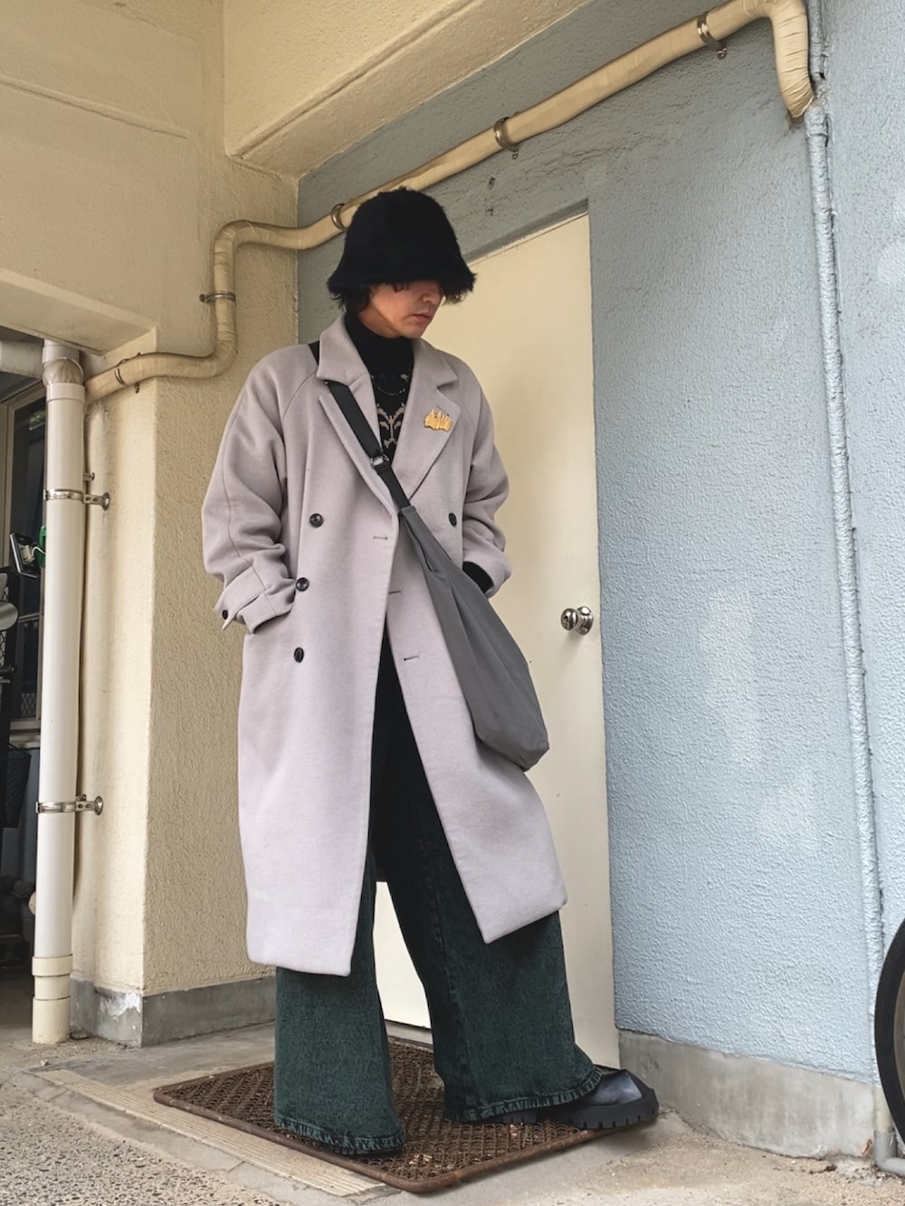 グレー系のショルダーバッグ、グレー系のチェスターコート、ブラック系のニット/セーターを着用したメンズの冬コーディネートの3枚目の写真