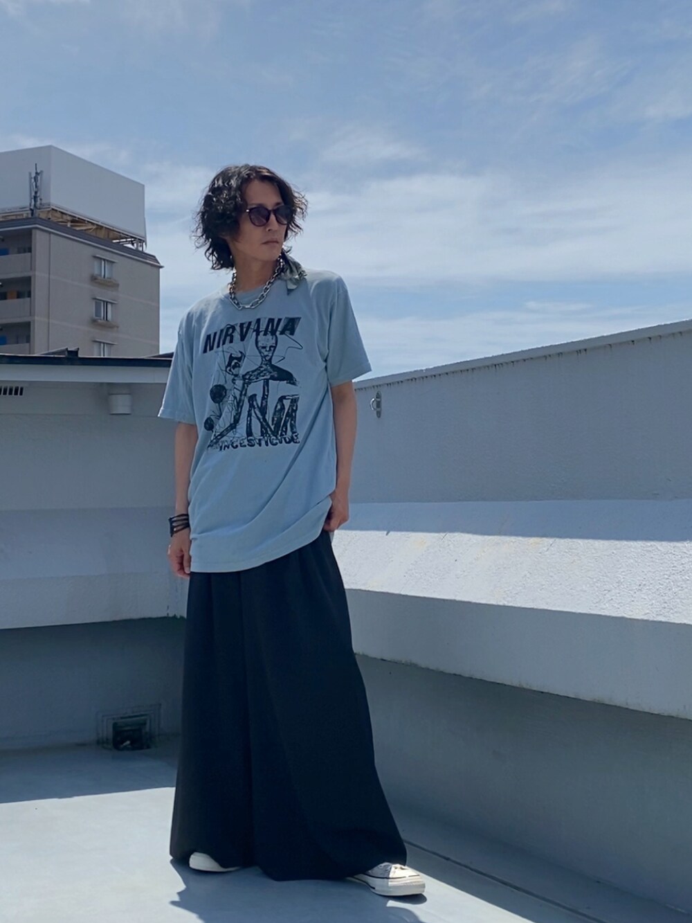 グリーン系のTシャツ/カットソー、ブラック系のスラックス、ベージュ系のスニーカーを着用したメンズの夏コーディネートの2枚目の写真