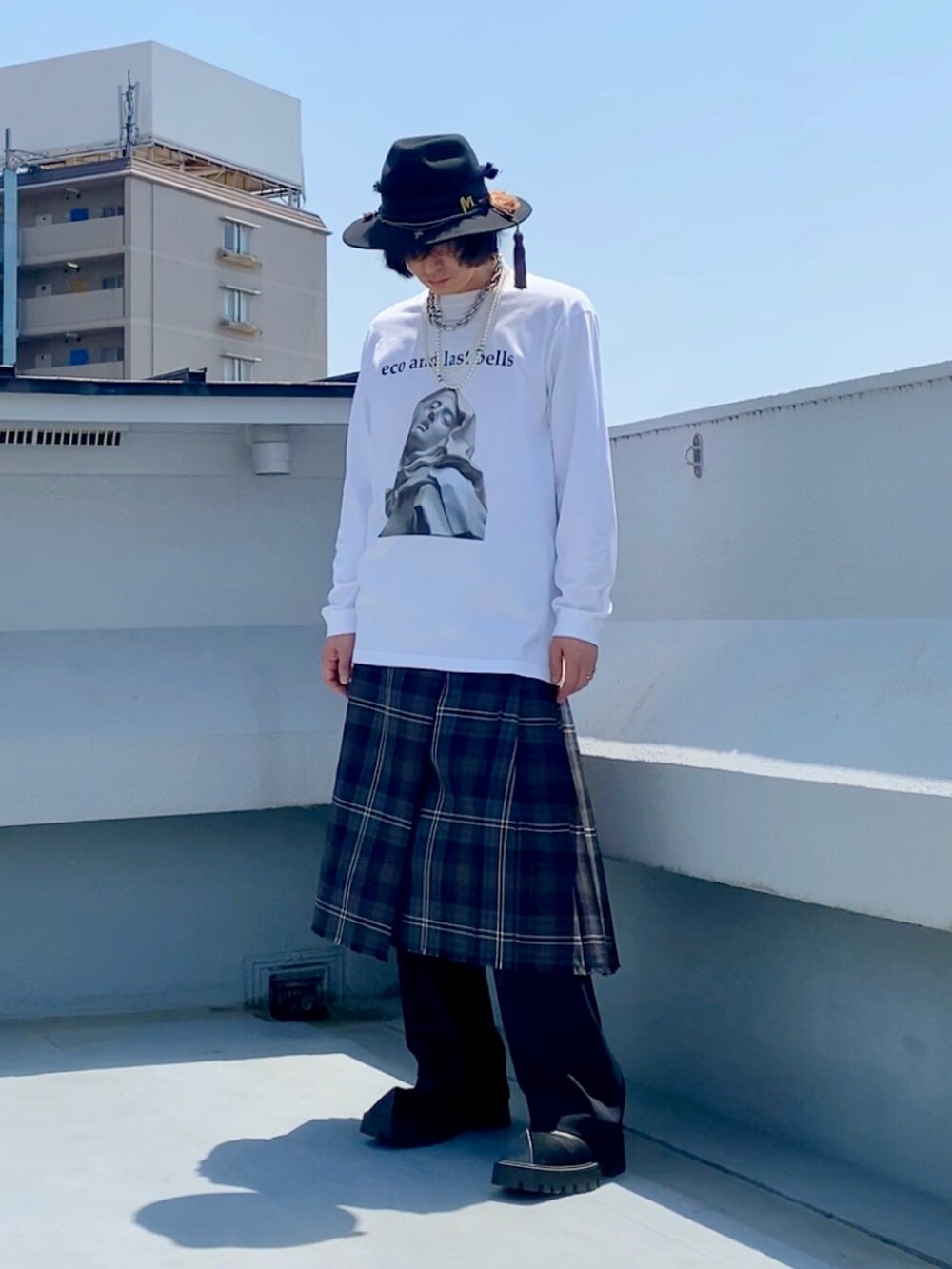 ホワイト系のTシャツ/カットソー、ブラウン系のスカート、ブラック系のスラックスを着用したメンズの春コーディネートの2枚目の写真