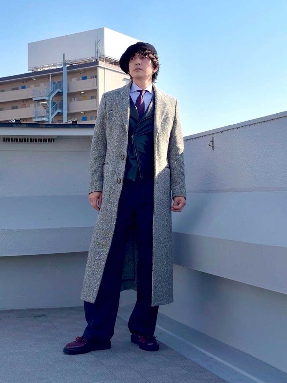 ベージュ系のチェスターコート、ブラック系のライダースジャケット、グレー系のスラックスを着用したメンズの冬コーディネートの3枚目の写真