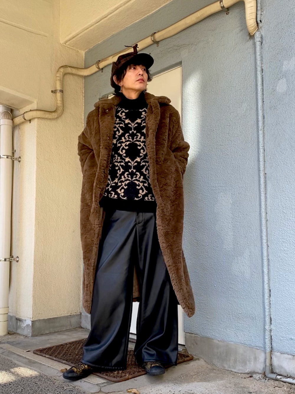 ブラック系のニット/セーター、ブラウン系のチェスターコート、ブラック系のその他パンツを着用したメンズの冬コーディネートの3枚目の写真