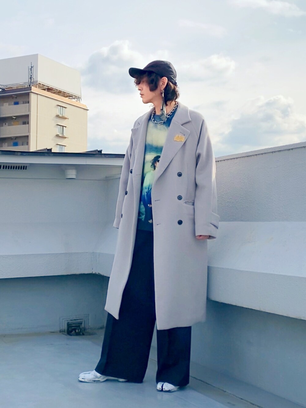 グレー系のチェスターコート、ブルー系のニット/セーター、ブラック系のスラックスを着用したメンズの冬コーディネートの4枚目の写真