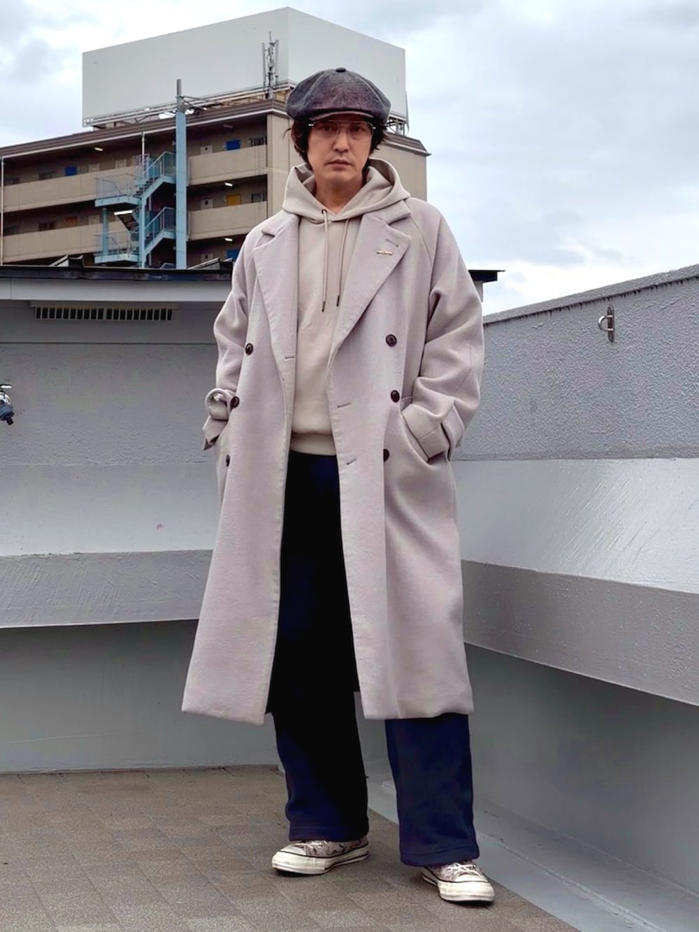 グレー系のチェスターコート、ベージュ系のパーカー、グレー系のその他パンツを着用したメンズの冬コーディネートの3枚目の写真