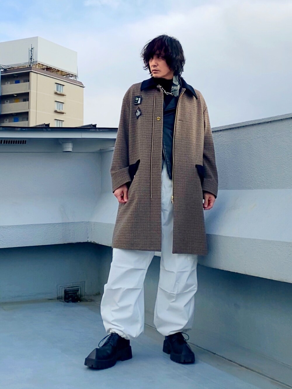 ブラック系のライダースジャケット、ブラウン系のステンカラーコート、ホワイト系のカーゴパンツを着用したメンズの冬コーディネートの4枚目の写真