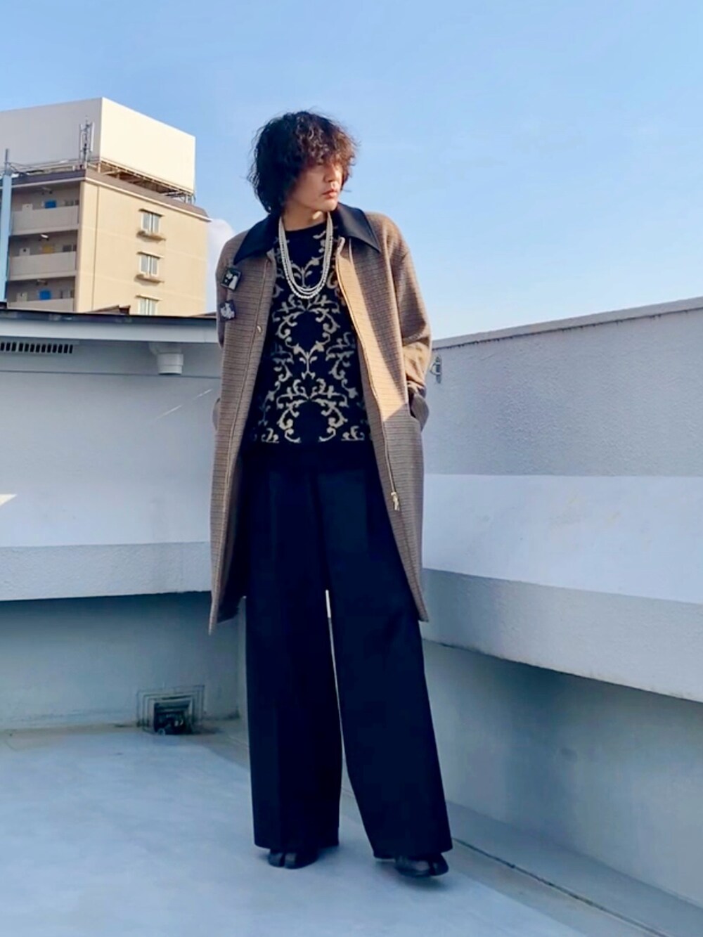 ブラウン系のステンカラーコート、ブラック系のニット/セーター、ブラック系のスラックスを着用したメンズの冬コーディネートの4枚目の写真