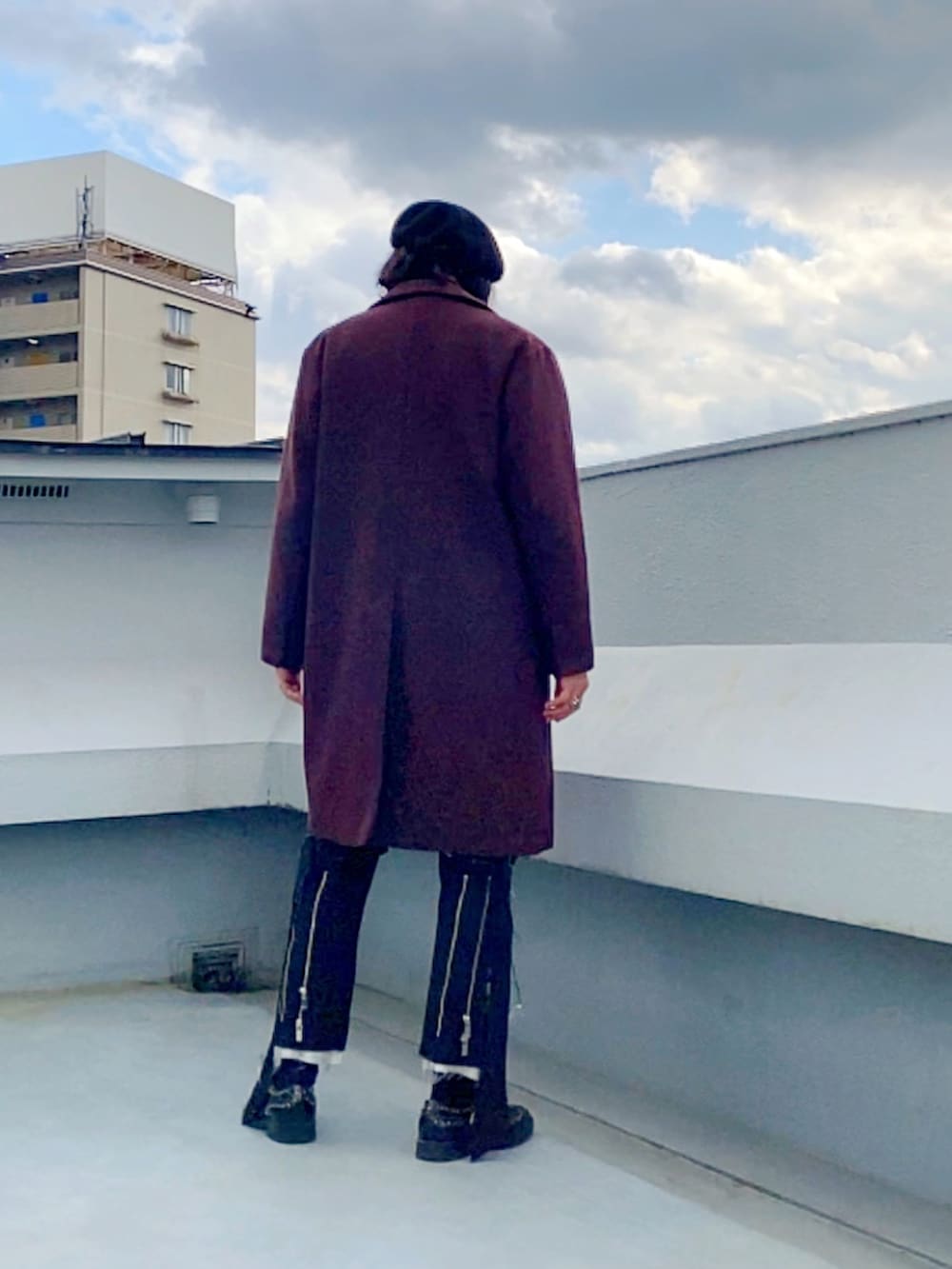 レッド系のチェスターコート、ブラック系のニット/セーター、ブラック系のその他パンツを着用したメンズの冬コーディネートの3枚目の写真