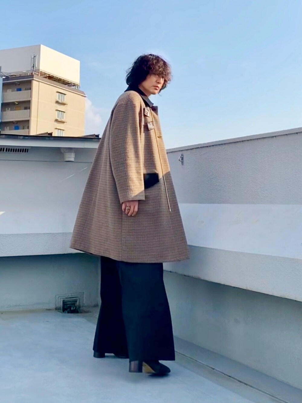 ブラウン系のステンカラーコート、ブラック系のニット/セーター、ブラック系のスラックスを着用したメンズの冬コーディネートの3枚目の写真