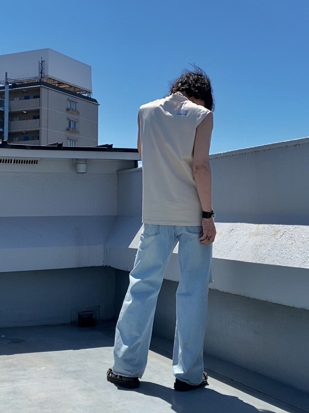 ベージュ系のTシャツ/カットソー、ブルー系のデニムパンツ、ブラック系のサンダルを着用したメンズの夏コーディネートの3枚目の写真