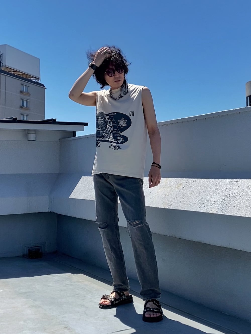 ベージュ系のTシャツ/カットソー、グレー系のデニムパンツ、ブラック系のサンダルを着用したメンズの夏コーディネートの3枚目の写真