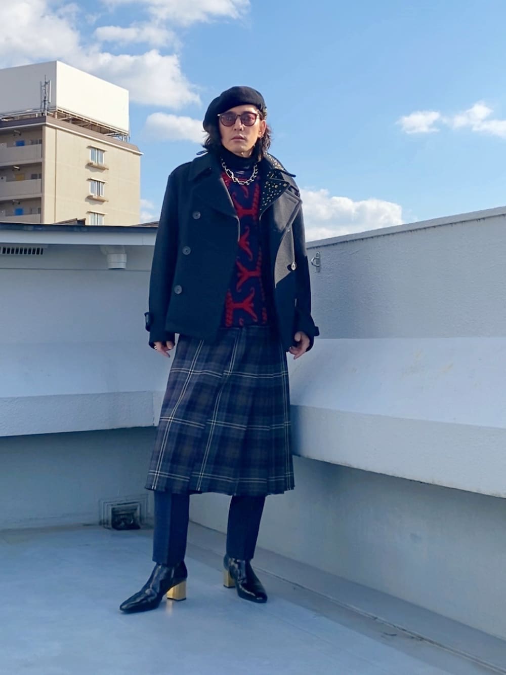 ブラック系のピーコート、レッド系のニット/セーター、ブラウン系のスカートを着用したメンズの冬コーディネートの3枚目の写真