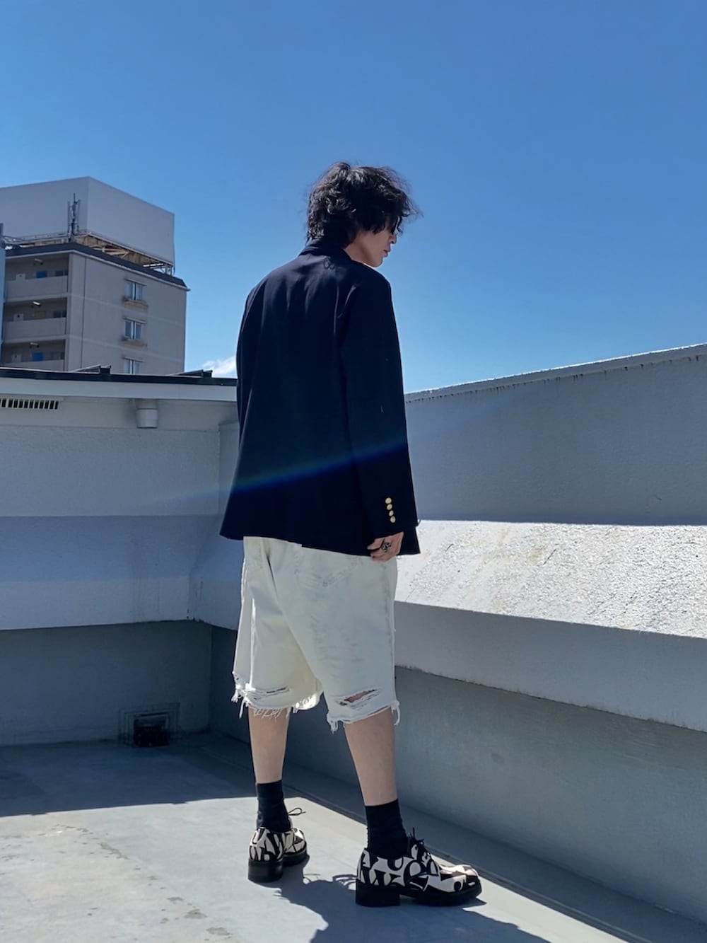 ホワイト系のタンクトップ、ブルー系のテーラードジャケット、ホワイト系のデニムパンツを着用したメンズの夏コーディネートの4枚目の写真