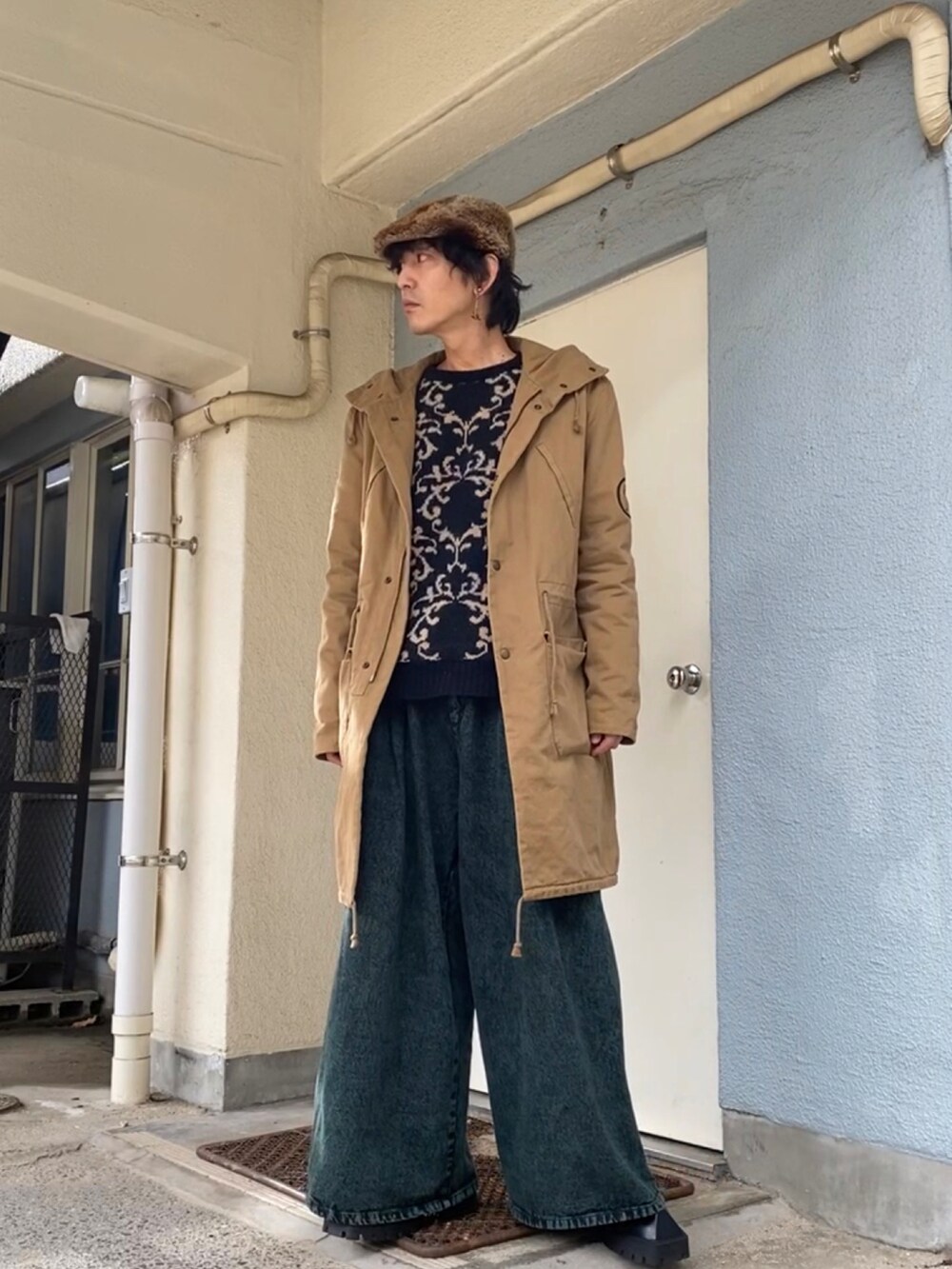 ブラック系のニット/セーター、ベージュ系のモッズコート、グリーン系のデニムパンツを着用したメンズの冬コーディネートの2枚目の写真