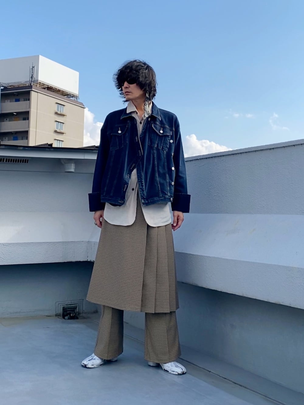 ブルー系のデニムジャケット、ベージュ系のスカート、ベージュ系のスラックスを着用したメンズの秋コーディネートの2枚目の写真