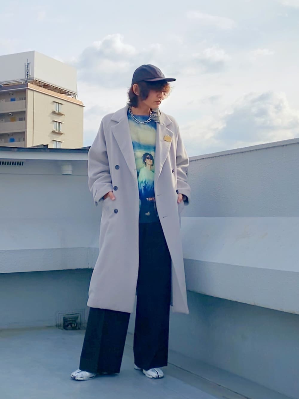 グレー系のチェスターコート、ブルー系のニット/セーター、ブラック系のスラックスを着用したメンズの冬コーディネートの3枚目の写真