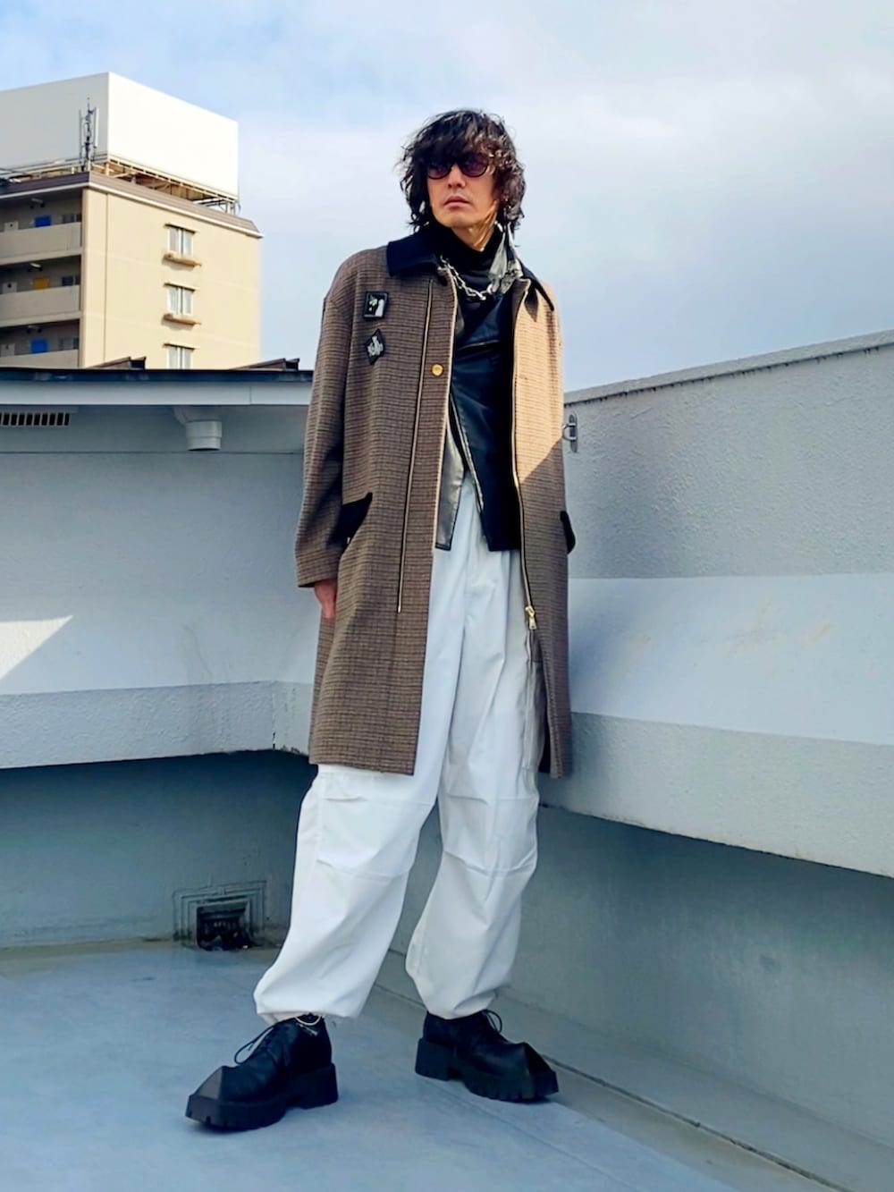 ブラック系のライダースジャケット、ブラウン系のステンカラーコート、ホワイト系のカーゴパンツを着用したメンズの冬コーディネートの2枚目の写真