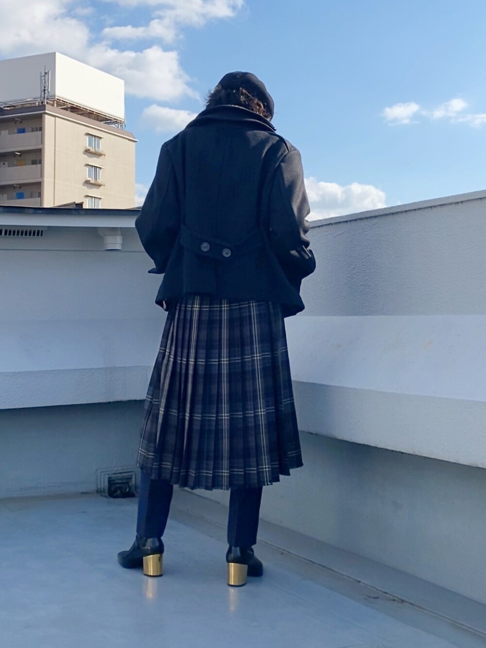 ブラック系のピーコート、レッド系のニット/セーター、ブラウン系のスカートを着用したメンズの冬コーディネートの5枚目の写真