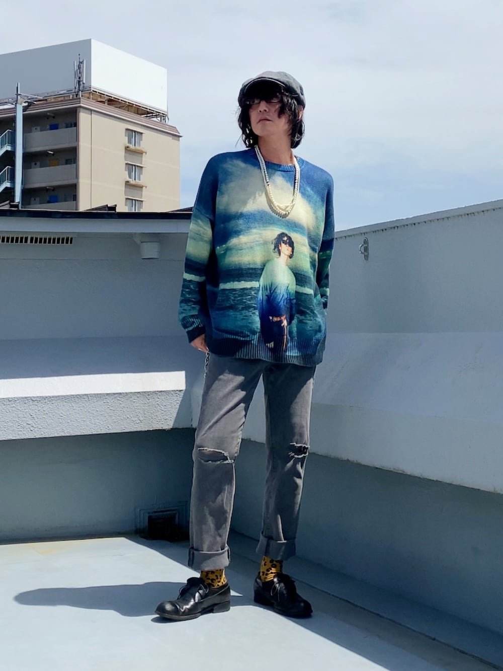 ブルー系のニット/セーター、グレー系のデニムパンツ、ブラック系のドレスシューズを着用したメンズの春コーディネートの3枚目の写真