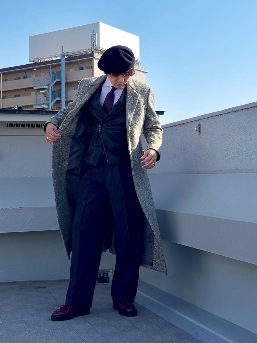 ベージュ系のチェスターコート、ブラック系のライダースジャケット、グレー系のスラックスを着用したメンズの冬コーディネートの5枚目の写真