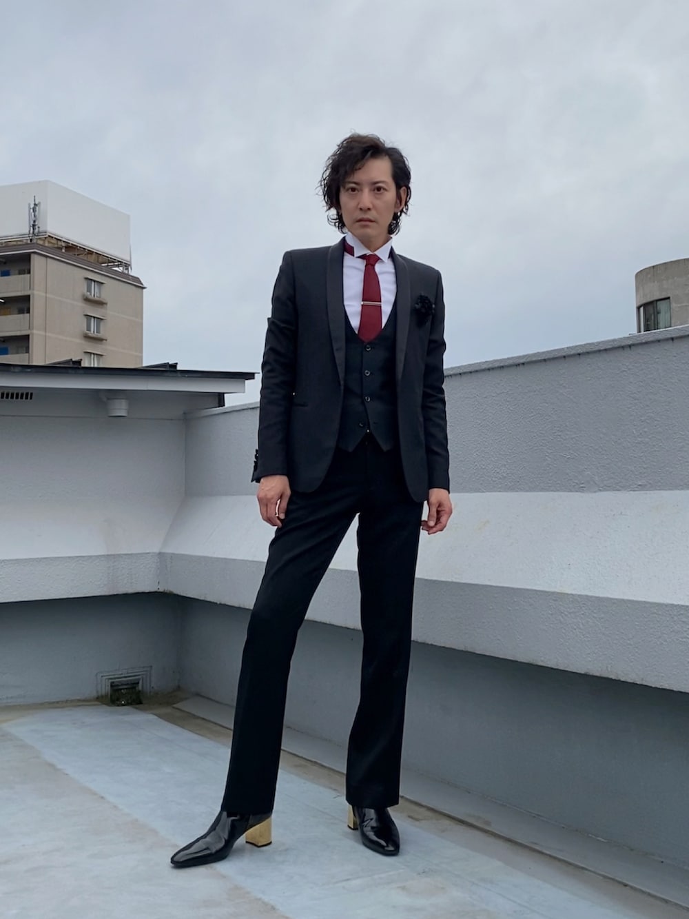 ブラック系のテーラードジャケット、ブラック系のブーツ、ブラック系のスラックスを着用したメンズの春コーディネートの3枚目の写真