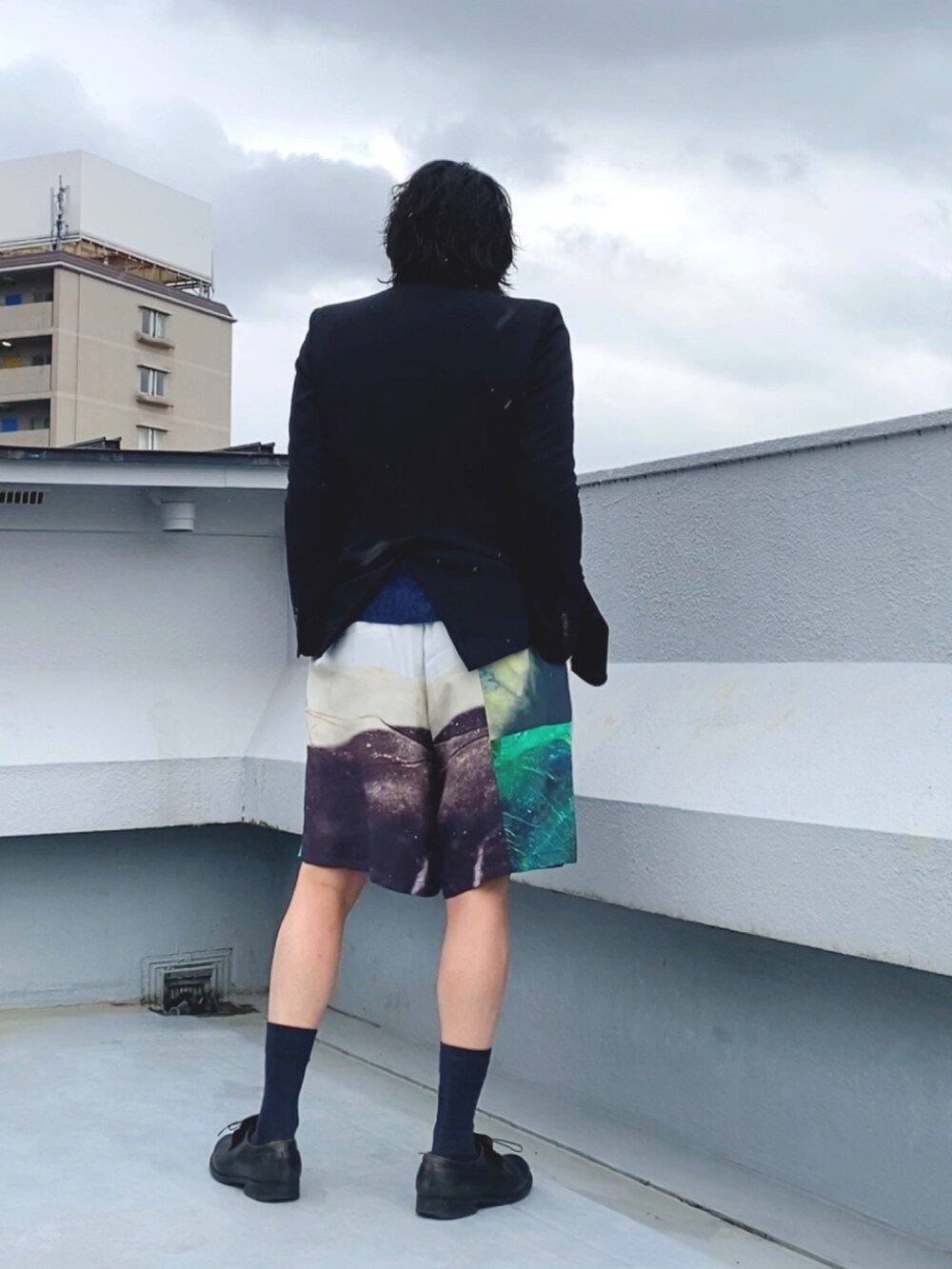 ブラック系のテーラードジャケット、ブルー系のニット/セーター、ホワイト系のその他パンツを着用したメンズの秋コーディネートの3枚目の写真