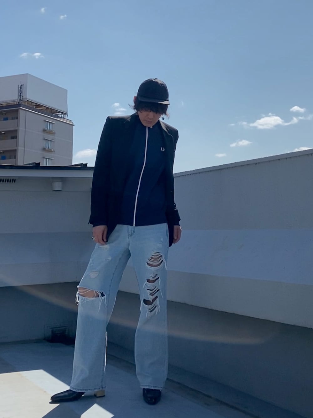 ブラック系のテーラードジャケット、ブルー系のジャージ、ブルー系のデニムパンツを着用したメンズの春コーディネートの2枚目の写真