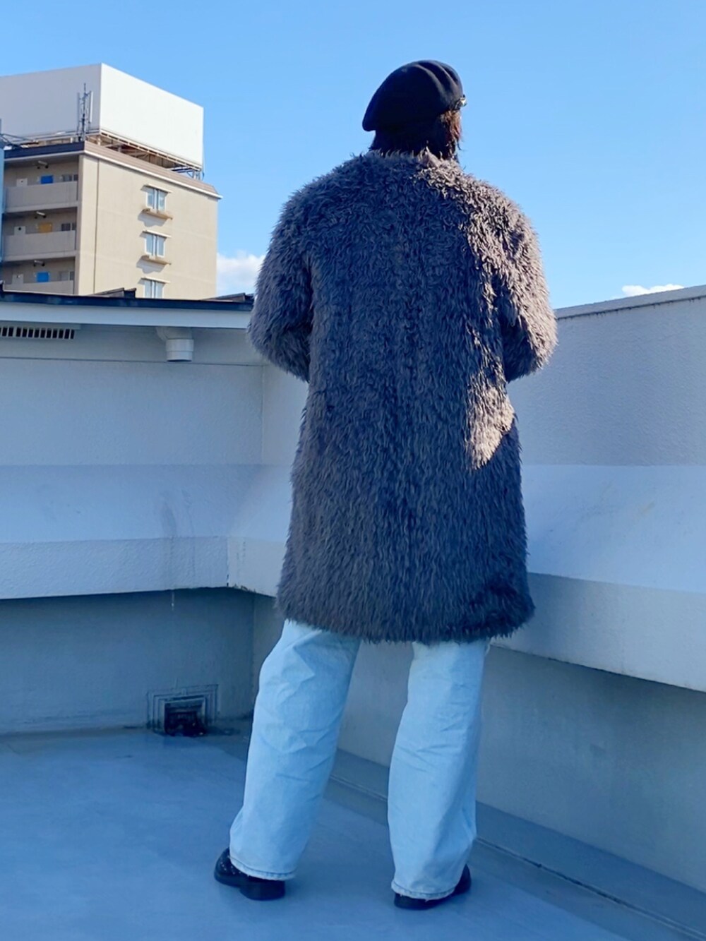 グレー系のノーカラーコート、レッド系のニット/セーター、ブラック系のニット/セーターを着用したメンズの冬コーディネートの4枚目の写真