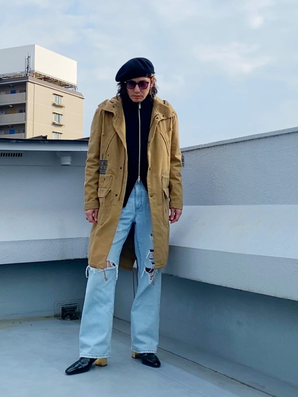 ベージュ系のモッズコート、ブラック系のニット/セーター、ブルー系のデニムパンツを着用したメンズの冬コーディネートの3枚目の写真