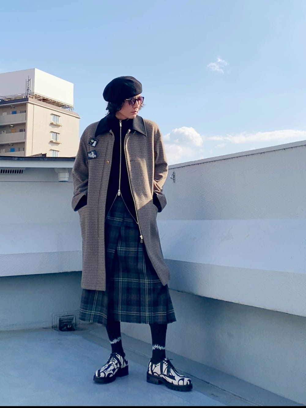 ブラウン系のステンカラーコート、ブラック系のニット/セーター、ブラウン系のスカートを着用したメンズの冬コーディネートの5枚目の写真