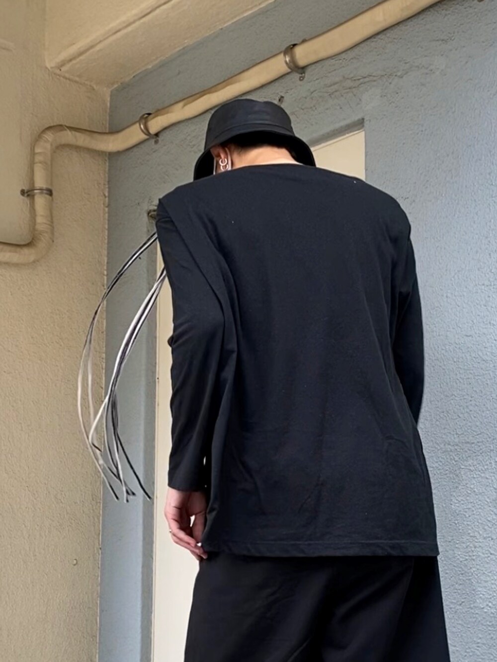 ホワイト系のサンダル、ブラック系のスラックス、ブラック系のTシャツ/カットソーを着用したメンズの夏コーディネートの3枚目の写真