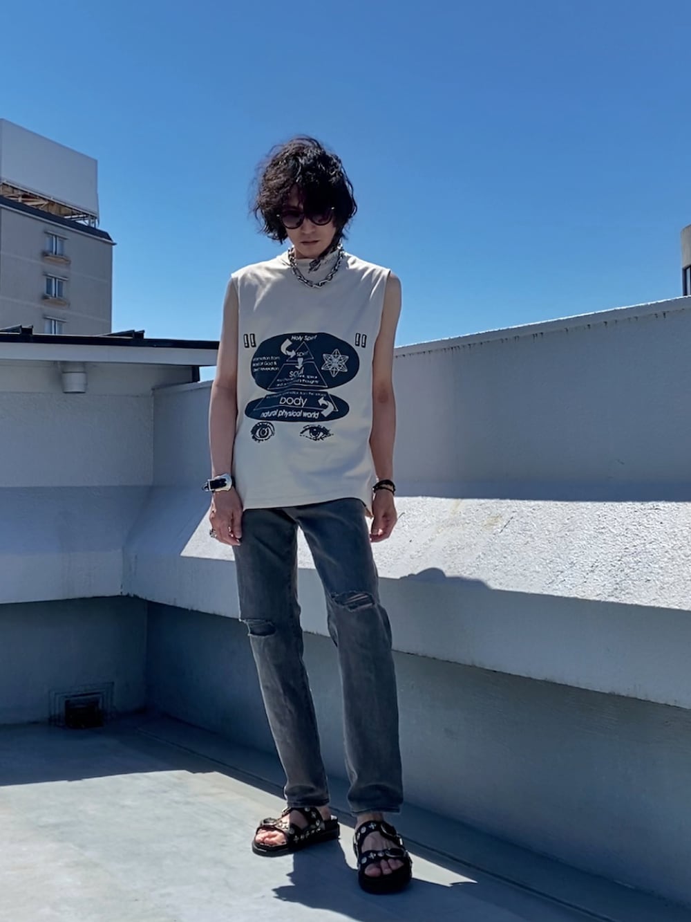 ベージュ系のTシャツ/カットソー、グレー系のデニムパンツ、ブラック系のサンダルを着用したメンズの夏コーディネートの2枚目の写真