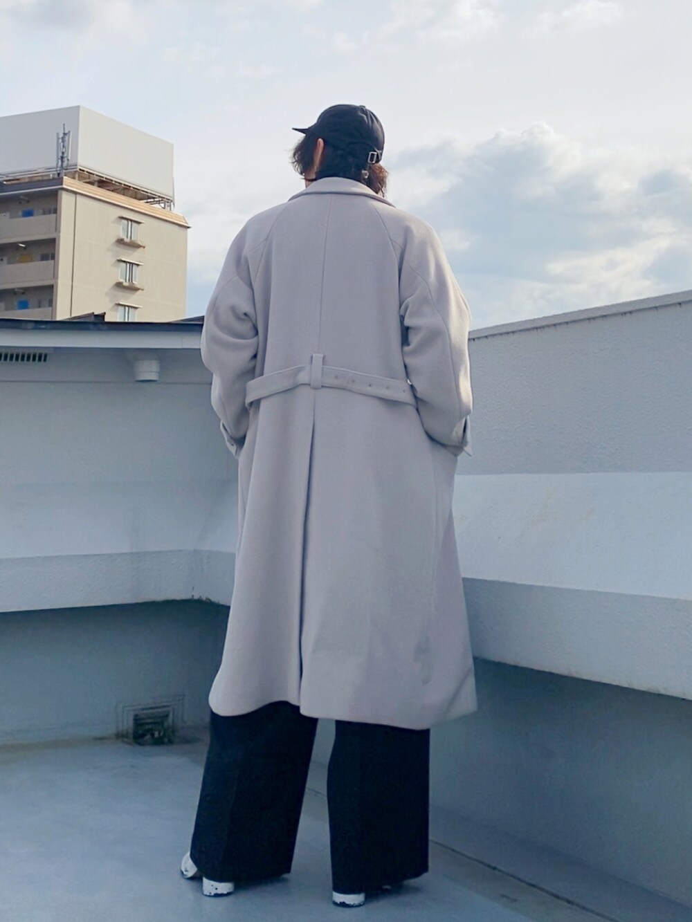 グレー系のチェスターコート、ブルー系のニット/セーター、ブラック系のスラックスを着用したメンズの冬コーディネートの5枚目の写真