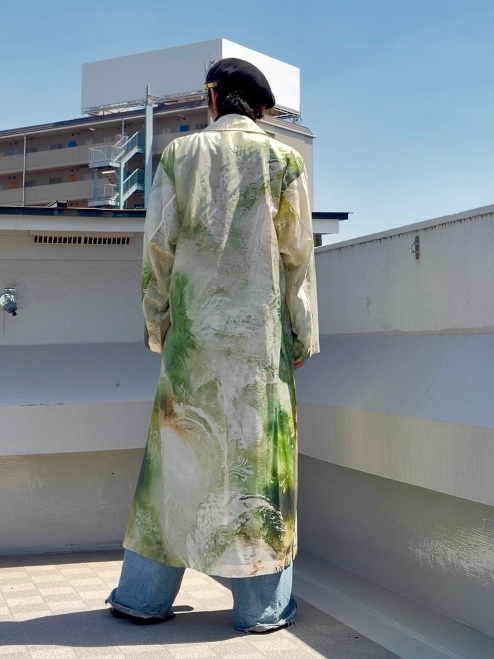 ブルー系のデニムパンツ、ブラック系のニット/セーター、グリーン系のステンカラーコートを着用したメンズの春コーディネートの5枚目の写真