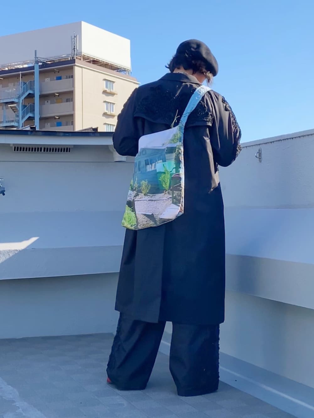 レッド系のニット/セーター、ブラック系のステンカラーコート、ブラック系のパンツを着用したメンズの冬コーディネートの4枚目の写真