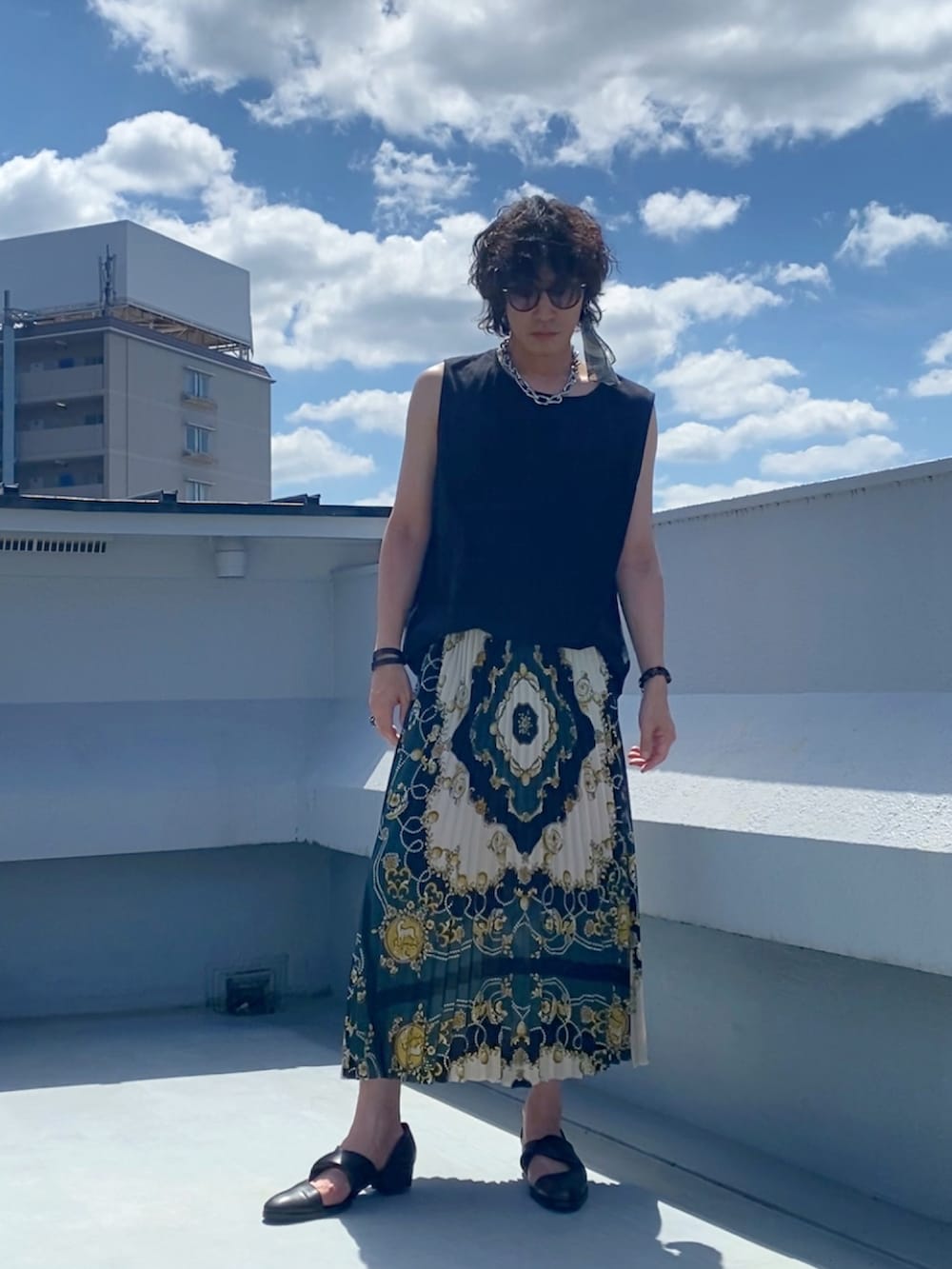 ブラック系のタンクトップ、グリーン系のスカート、ブラック系のブーツを着用したメンズの夏コーディネートの2枚目の写真