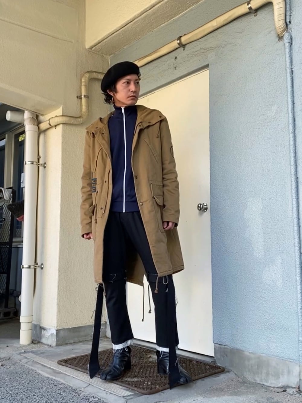 ベージュ系のモッズコート、ブルー系のジャージ、ブラック系のその他パンツを着用したメンズの冬コーディネートの3枚目の写真