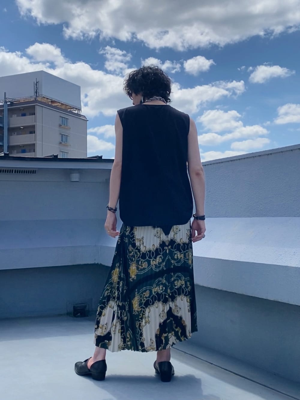 ブラック系のタンクトップ、グリーン系のスカート、ブラック系のブーツを着用したメンズの夏コーディネートの3枚目の写真