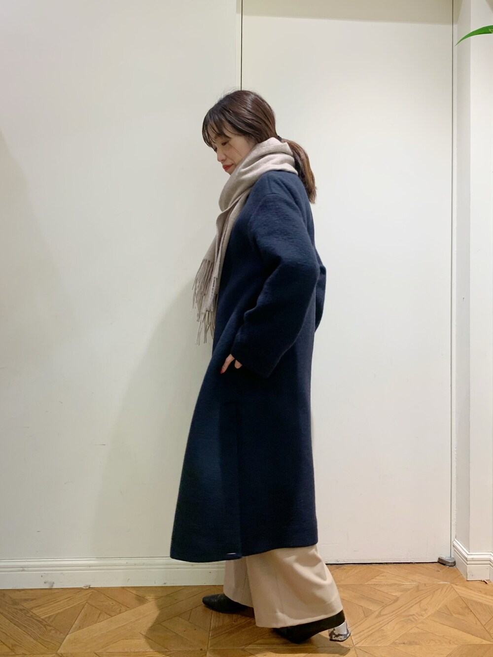 ブルー系のノーカラーコート、ベージュ系のスラックス、レッド系のトップスを着用したレディースの冬コーディネートの2枚目の写真