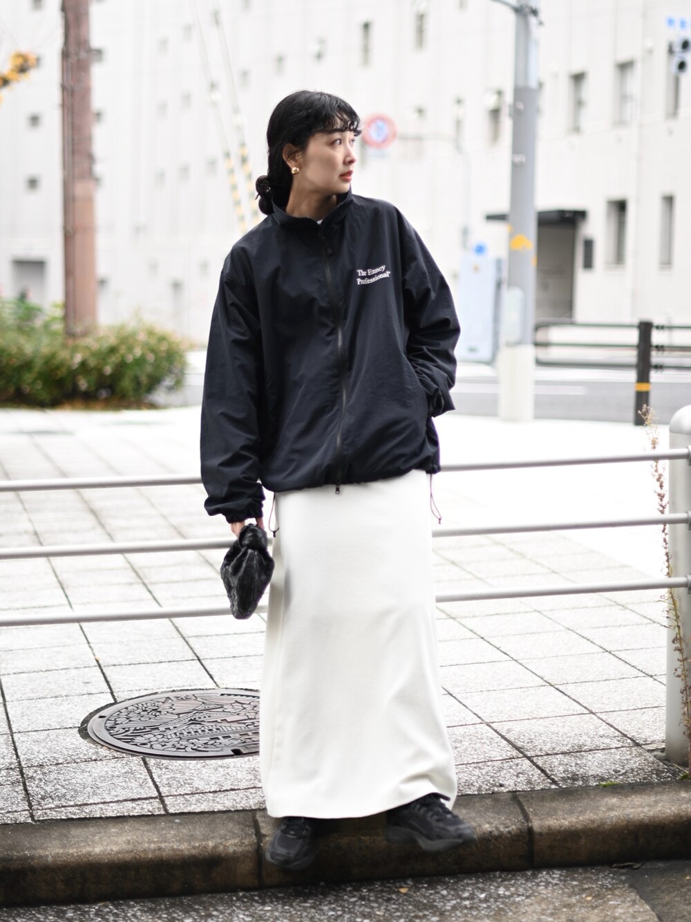 ブラック系のナイロンジャケット、ホワイト系のスカート、ブラック系のスニーカーを着用したレディースの冬コーディネートの2枚目の写真