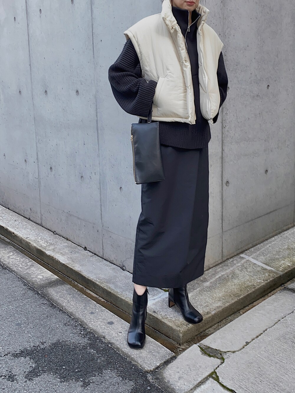ホワイト系のダウンベスト、ブラック系のニット/セーター、ブラック系のスカートを着用したレディースの冬コーディネートの2枚目の写真