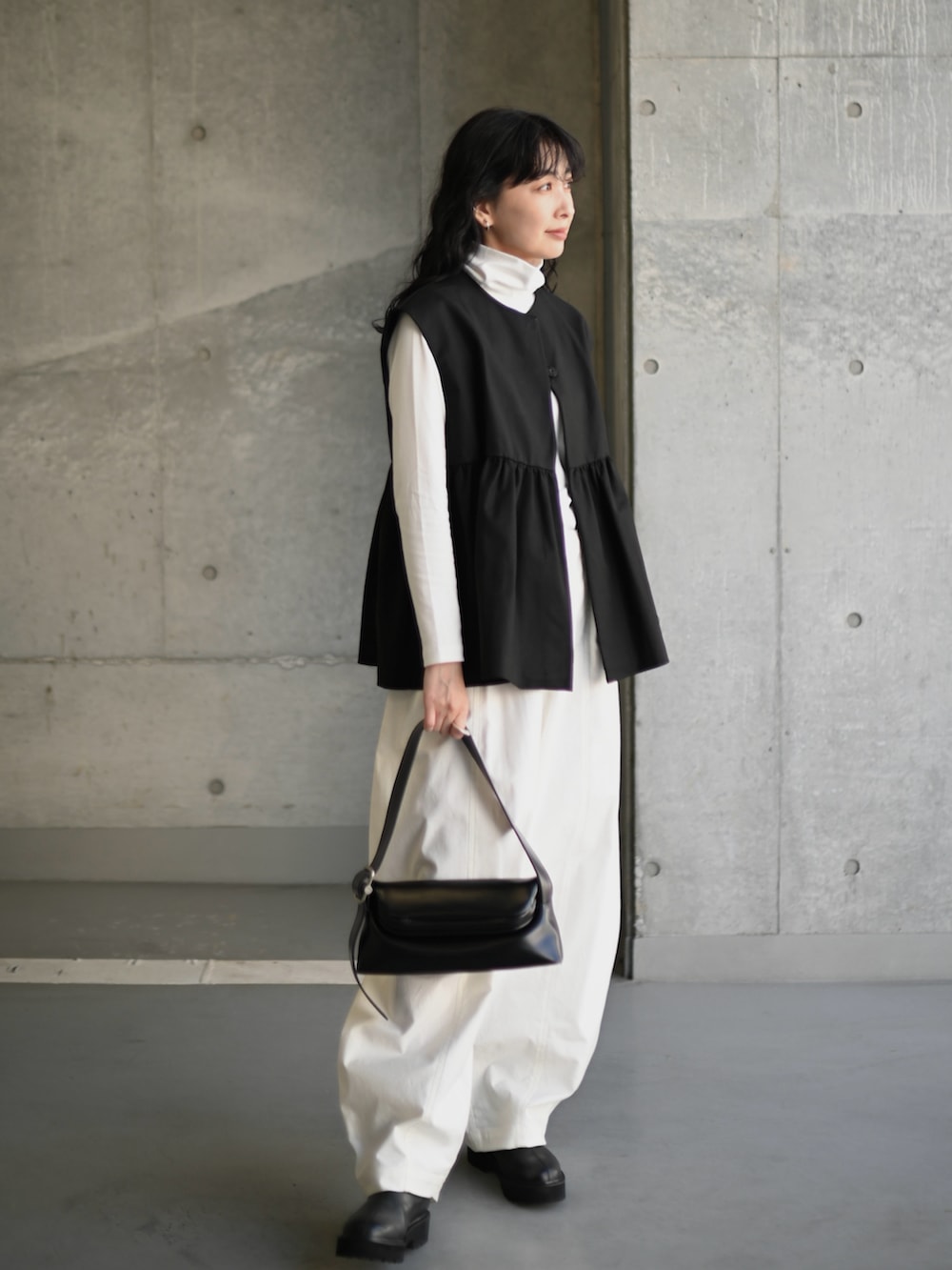 ブラック系のベスト、ホワイト系のTシャツ/カットソー、ホワイト系のチノパンツを着用したレディースの秋コーディネートの2枚目の写真