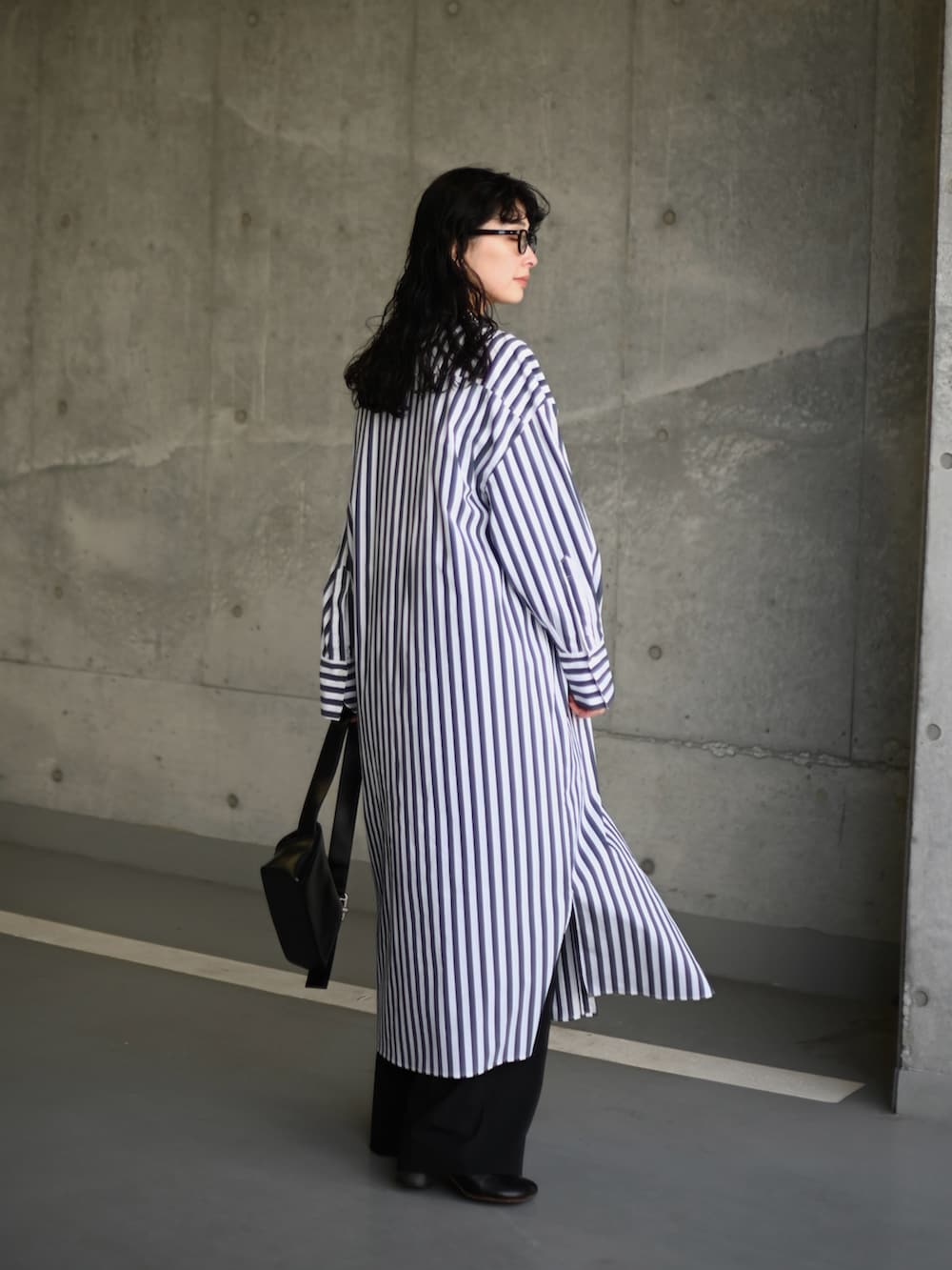 ホワイト系のシャツワンピース、ブラック系のショルダーバッグ、ブラック系のスラックスを着用したレディースの冬コーディネートの2枚目の写真