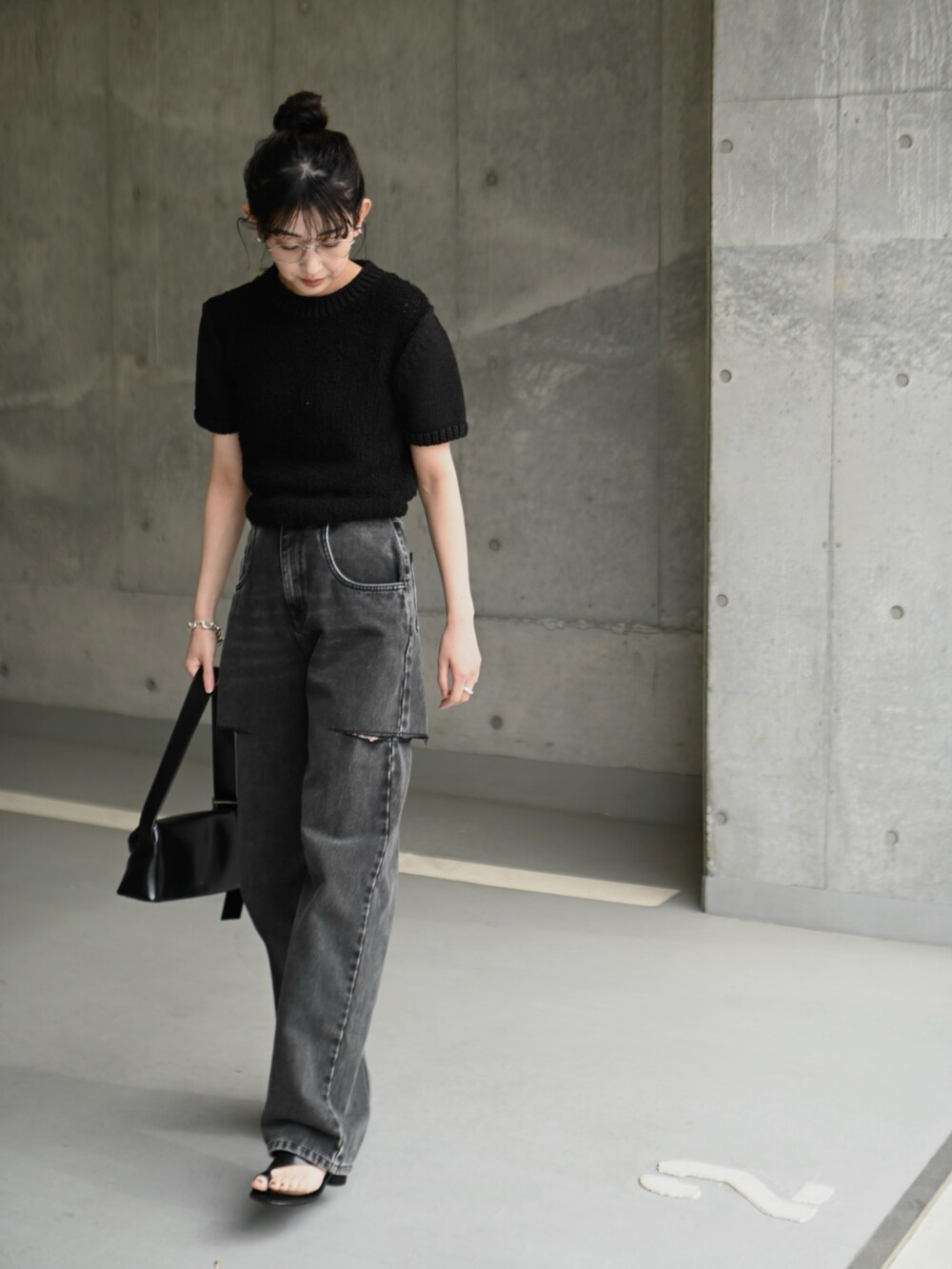 ブラック系のデニムパンツ、ブラック系のショルダーバッグ、ブラック系のニット/セーターを着用したレディースの春コーディネートの4枚目の写真