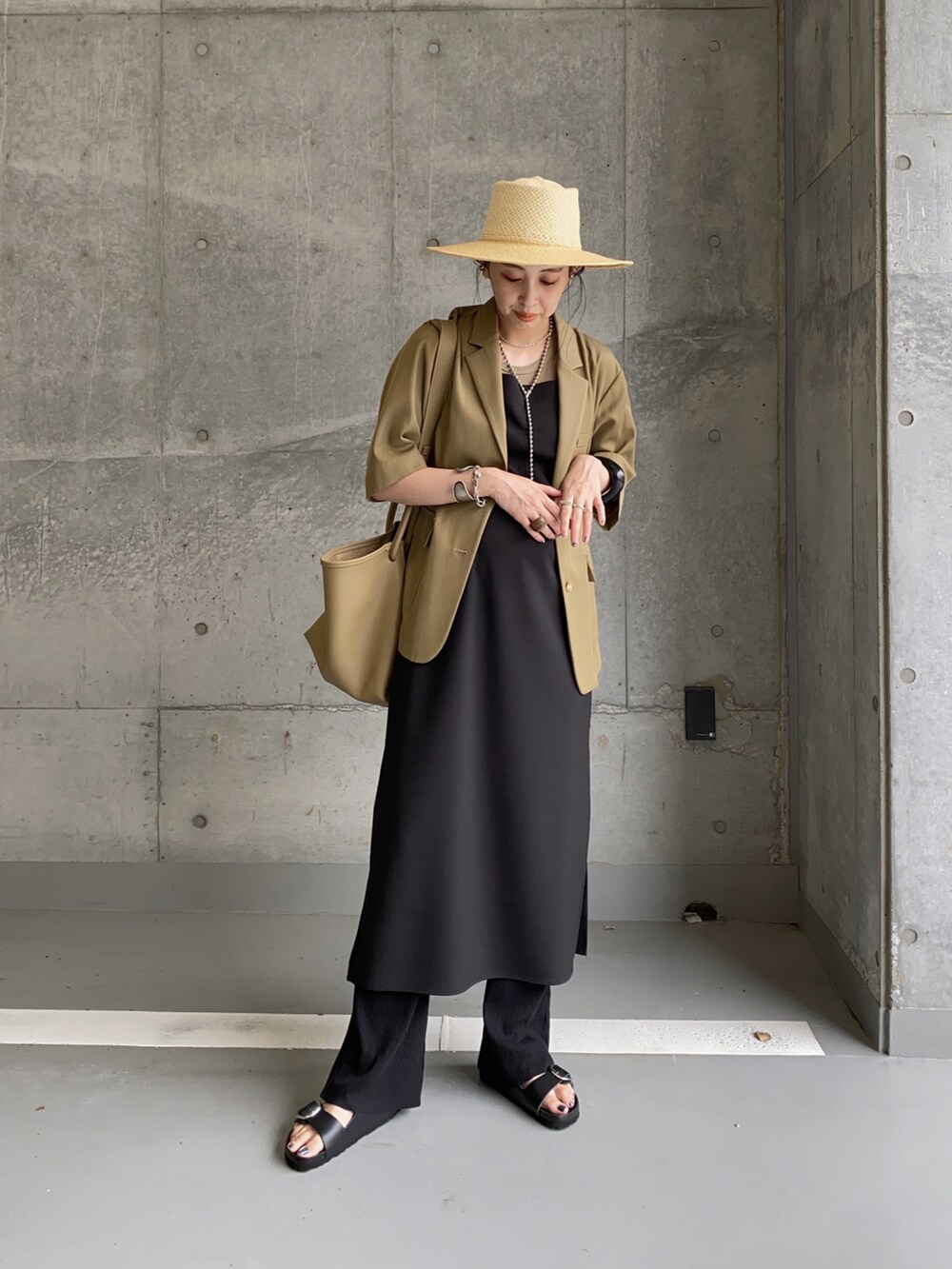 グリーン系のテーラードジャケット、ブラック系のワンピース、ブラック系のサンダルを着用したレディースの夏コーディネートの3枚目の写真