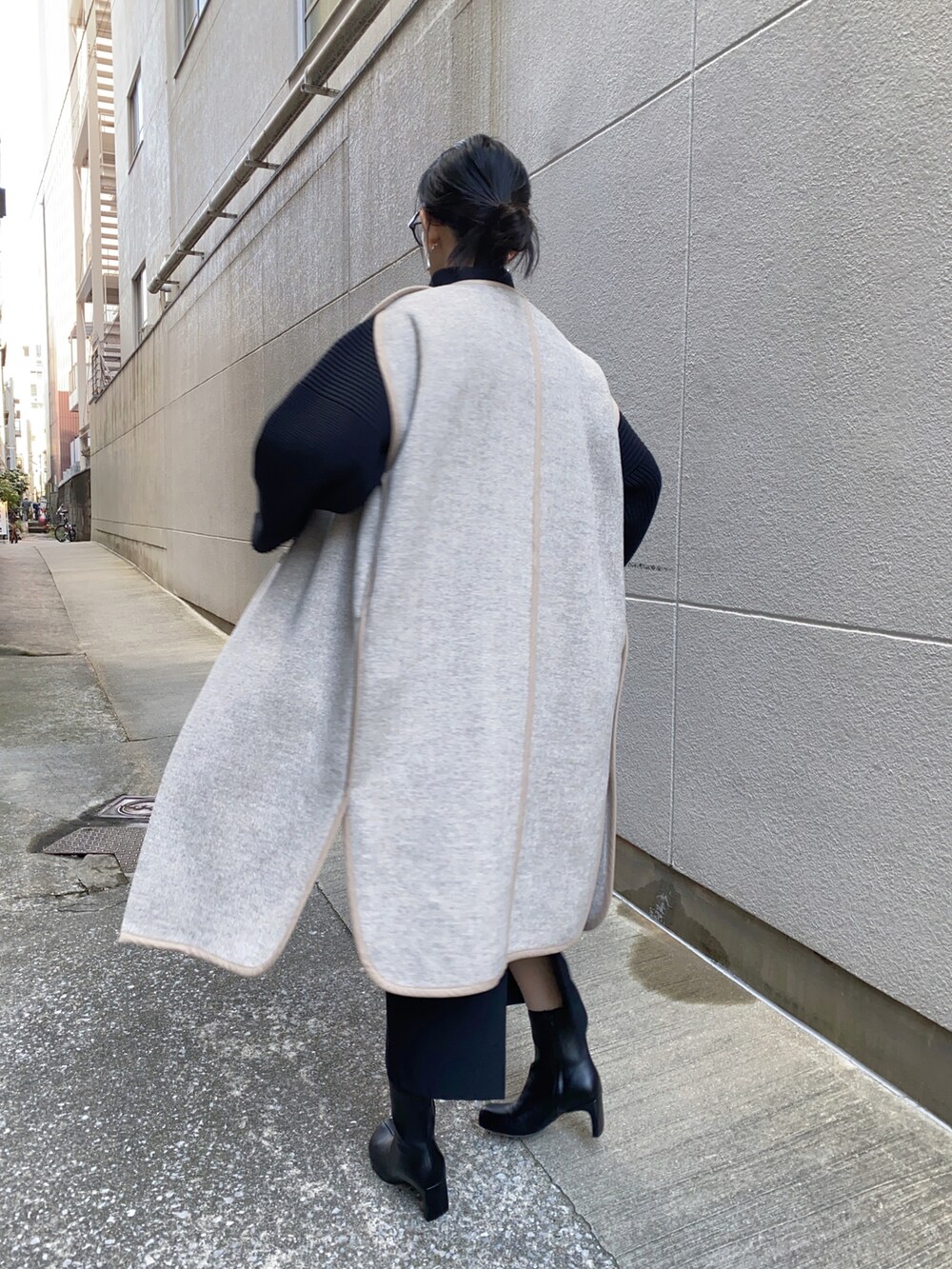 ベージュ系のその他アウター、ブラック系のニット/セーター、ブラック系のブーツを着用したレディースの冬コーディネートの2枚目の写真