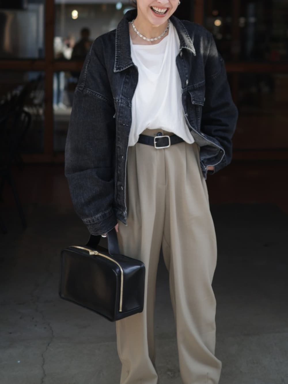 ブラック系のデニムジャケット、ブラック系のハンドバッグ、ブラック系のブーツを着用したレディースの冬コーディネートの4枚目の写真