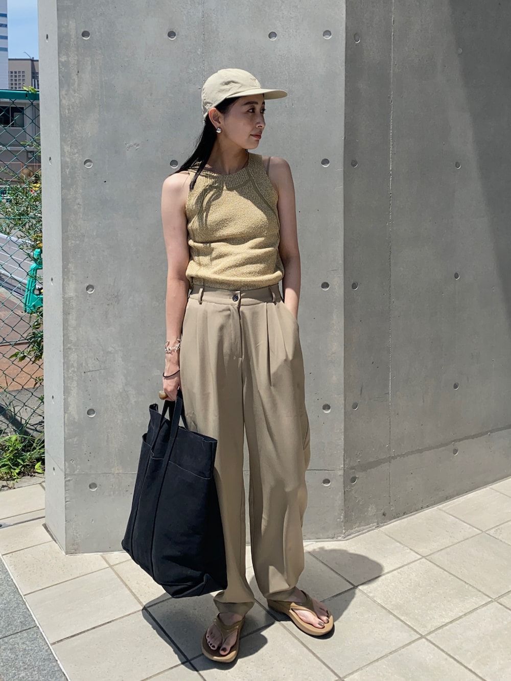 グリーン系のタンクトップ、ブラック系のトートバッグ、ベージュ系のサンダルを着用したレディースの夏コーディネートの2枚目の写真
