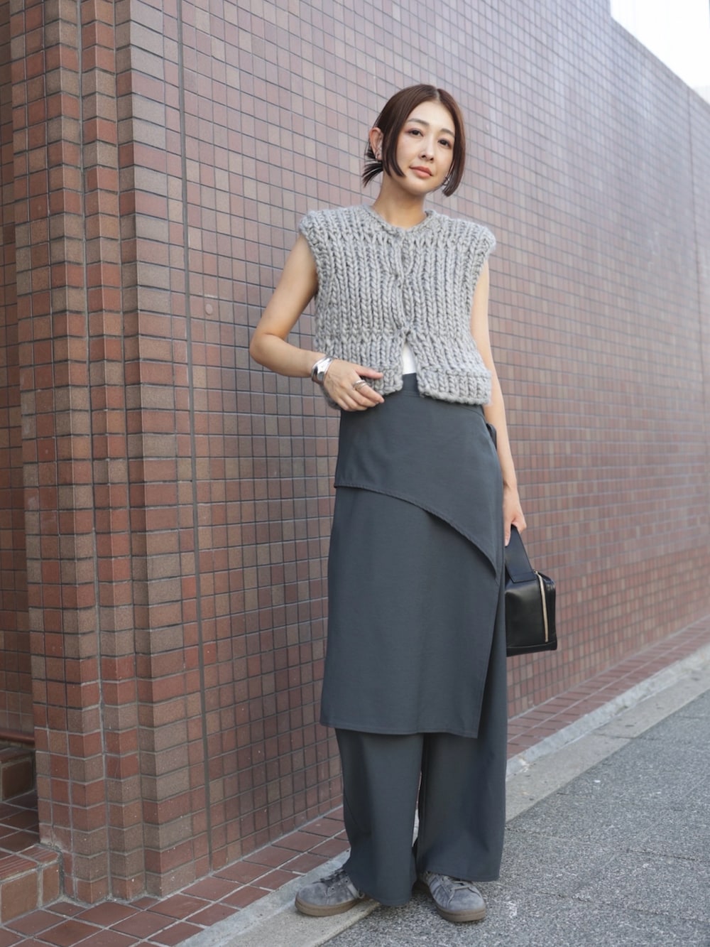 グレー系のスラックス、グレー系のスニーカー、ホワイト系のチューブトップを着用したレディースの秋コーディネートの2枚目の写真